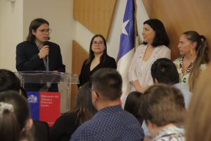 Hombre usando lentes de melena dando unas palabras en microfono, a su lado mujer representante de SENCE, y dos mujeres terapeutas ocupacionales de las escuelas