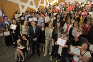 En la foto aparecen muchas personas posando, estudiantes con sus diplomas, familias y representantes del proyecto